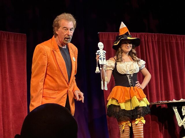 David Seebach onstage with an assistant in a witch costume holding a dancing skeleton